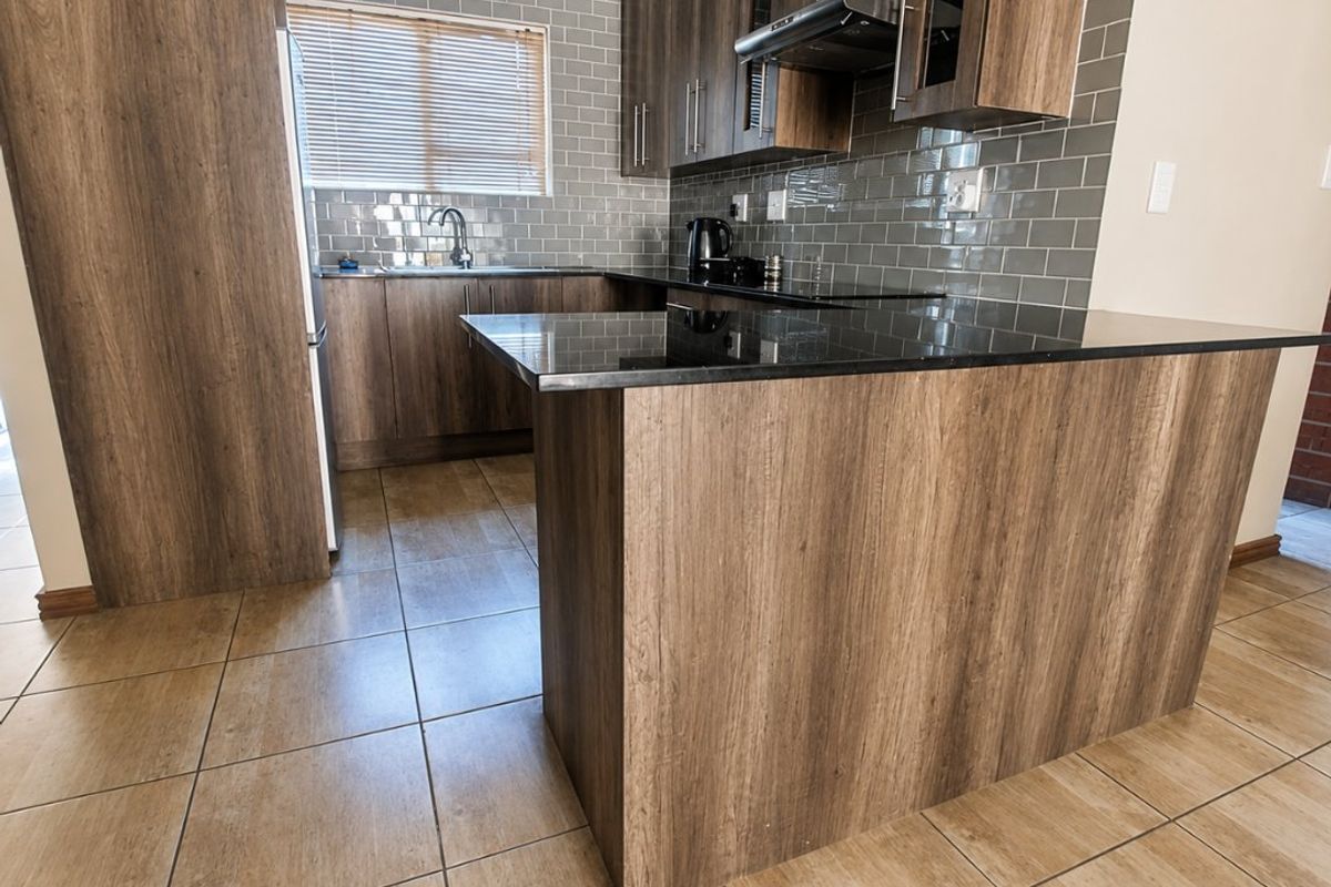 Modern kitchen featuring dark wood-look cabinetry, black granite countertops, subway tile backsplash, and durable ceramic floor tiles.