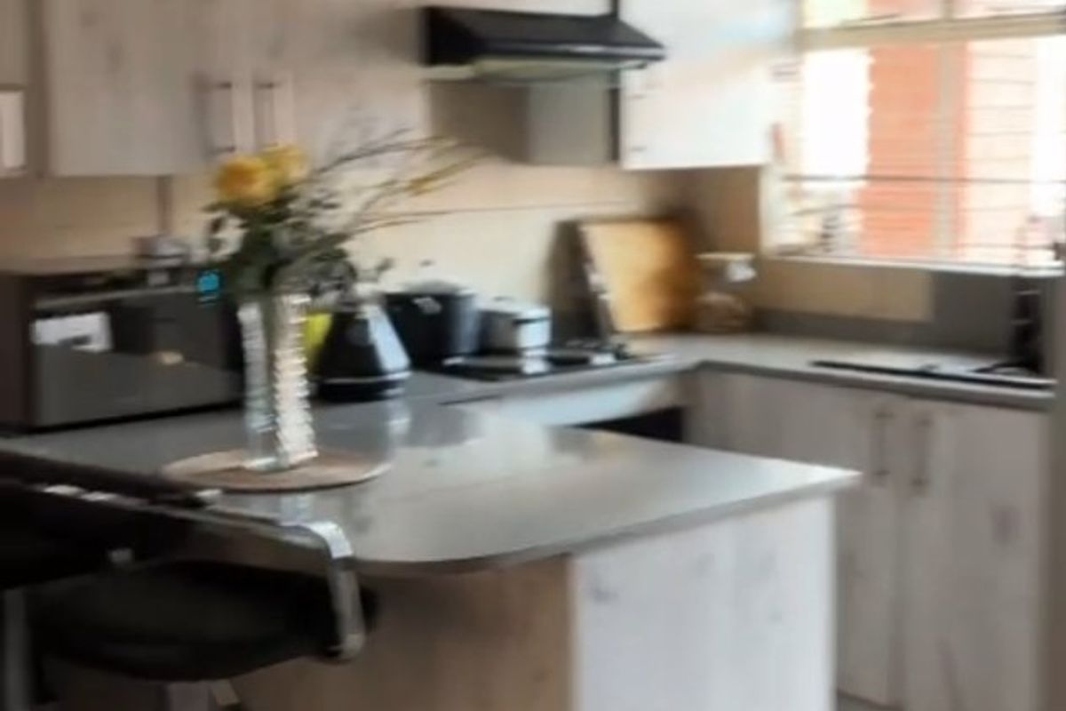 A functional kitchen featuring light-toned built-in cabinetry, a breakfast counter, integrated hob, and extractor fan with tiled flooring.