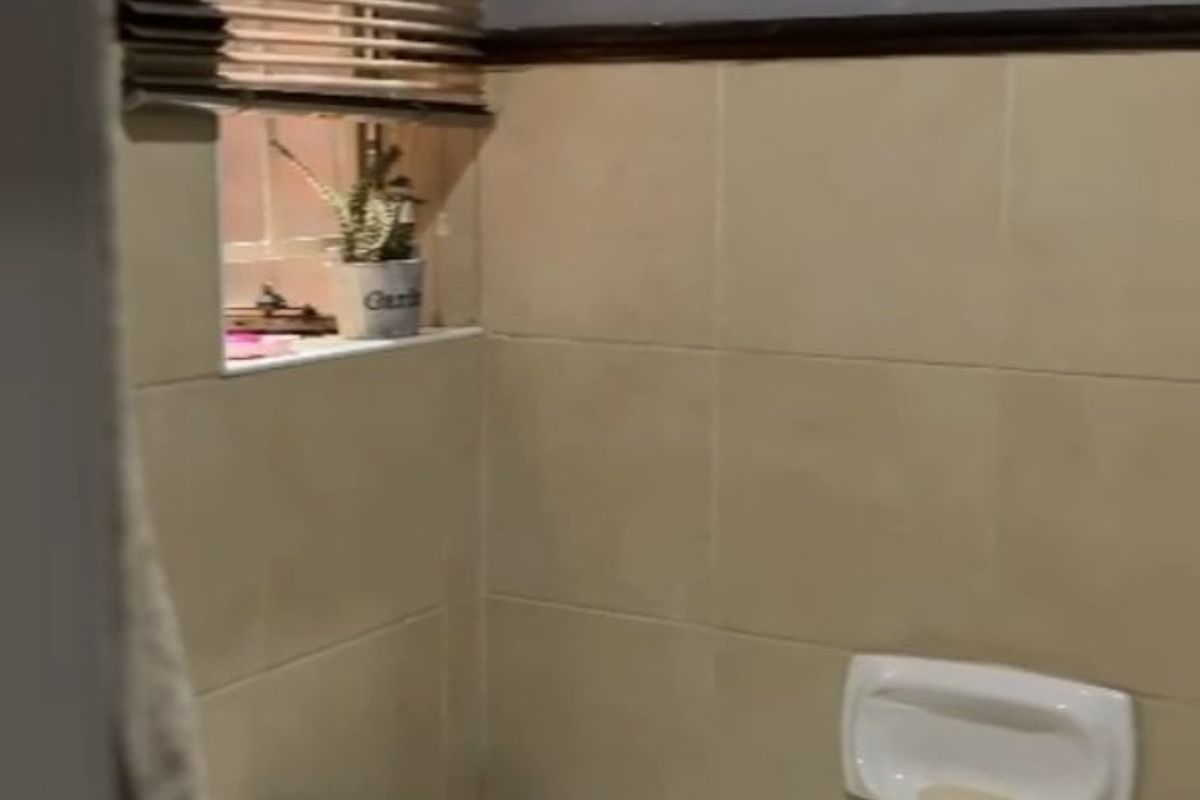 A compact bathroom featuring a standard bathtub with wall-mounted faucet, tiled splashback, and a window with a venetian blind.