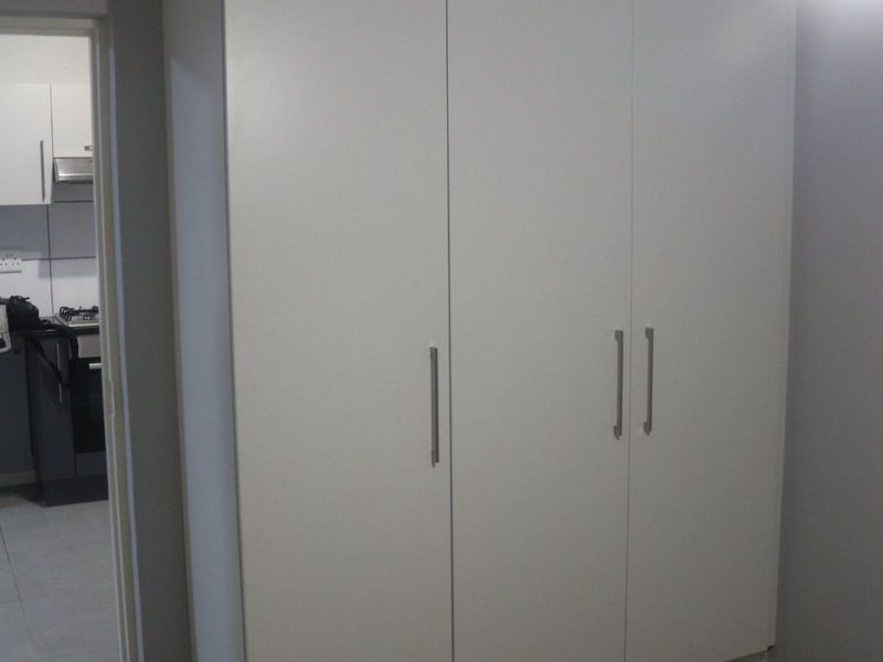 A bedroom featuring a clean, white built-in wardrobe with modern handles, offering ample storage space.