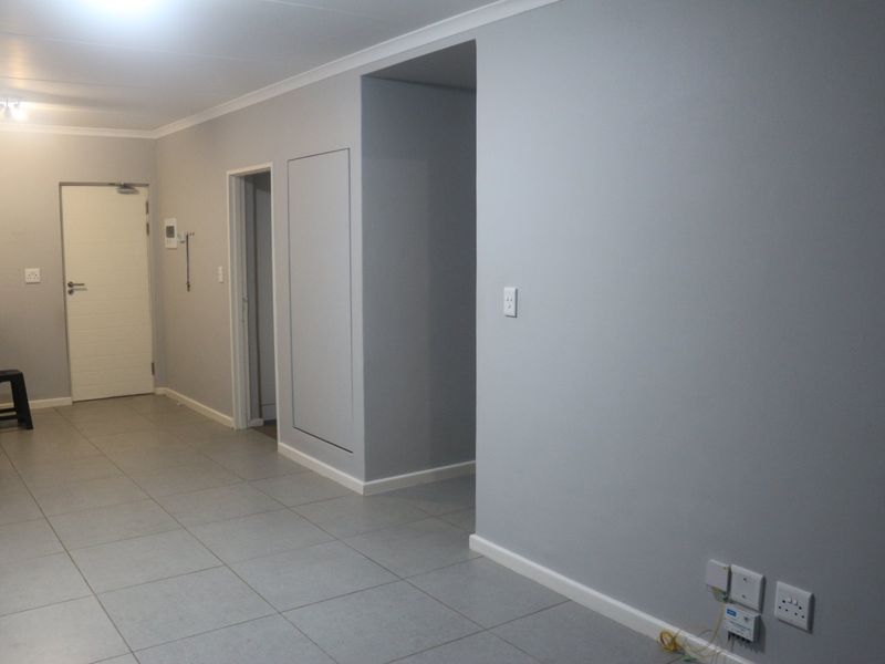 An open-plan living area featuring neutral grey walls, tiled flooring, and coved cornicing, providing a clean and versatile space for interior design.