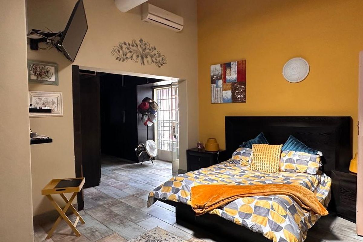 Spacious bedroom featuring exposed beam ceilings, tiled flooring, and a split system air conditioner, with an adjoining walk-in closet area.