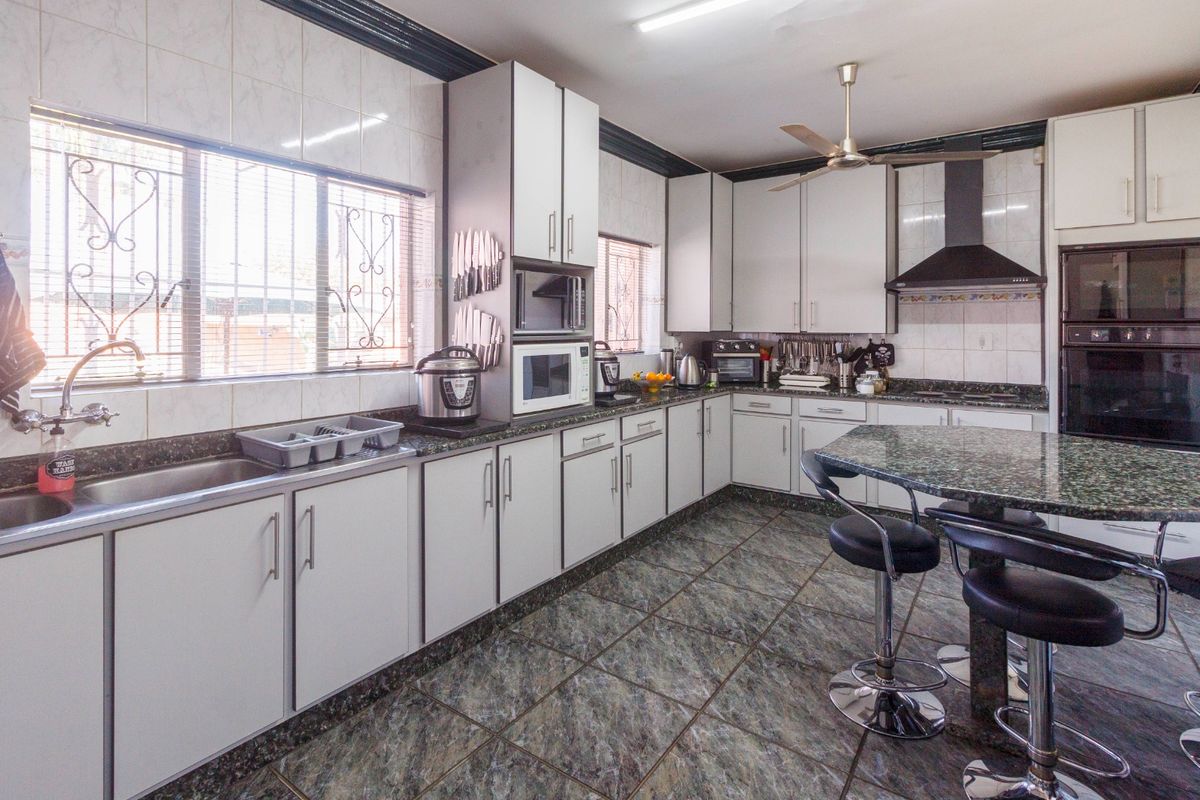 Spacious kitchen featuring granite countertops, built-in cabinetry, integrated oven, extractor fan, and tiled flooring with ample workspace.