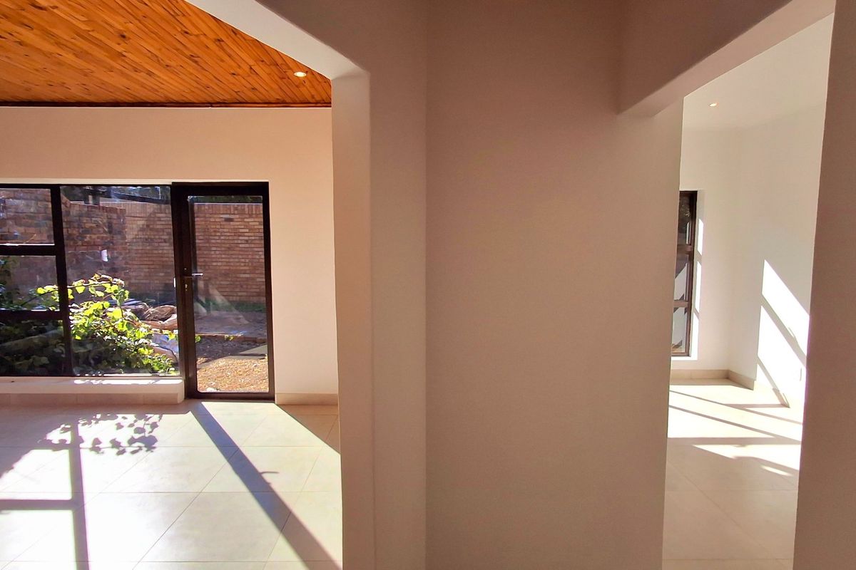 Bright and spacious living area featuring a warm timber-clad ceiling, neutral tiled flooring, and large glass doors providing seamless access to the outdoor space.