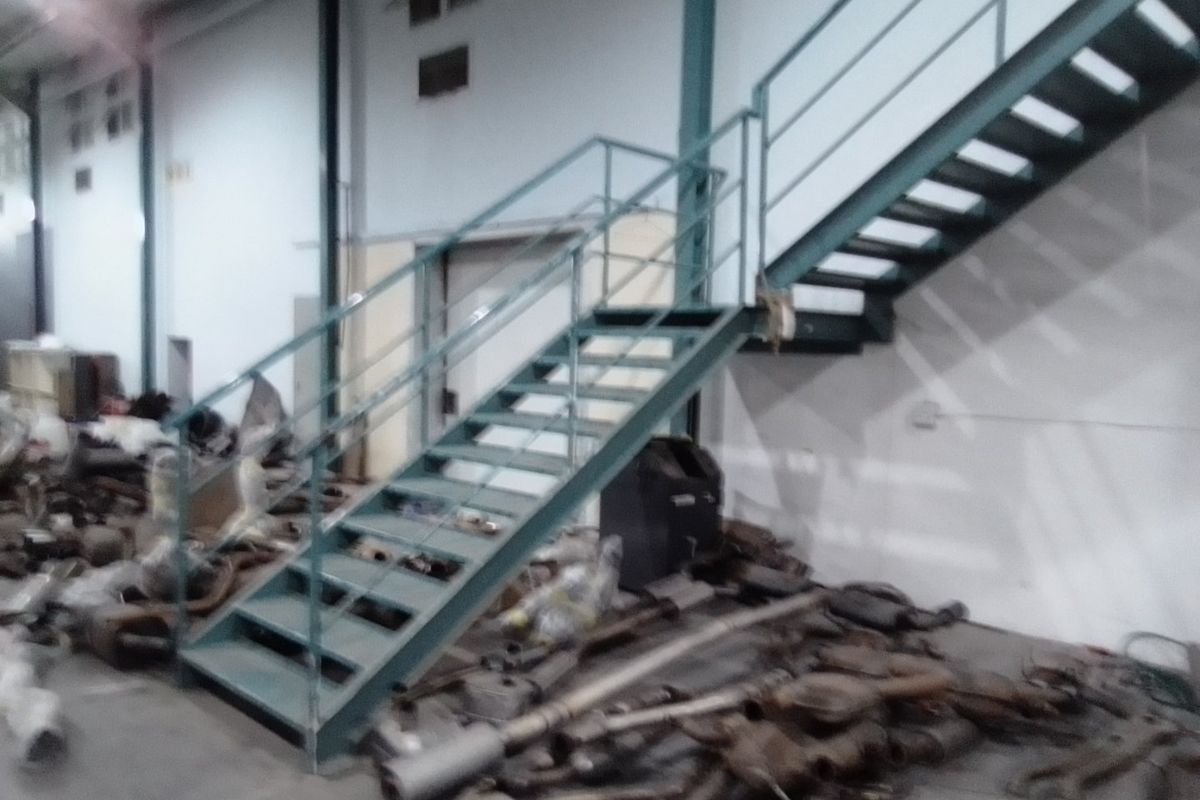 Industrial utility space featuring a metal staircase with steel handrails and exposed structural columns.