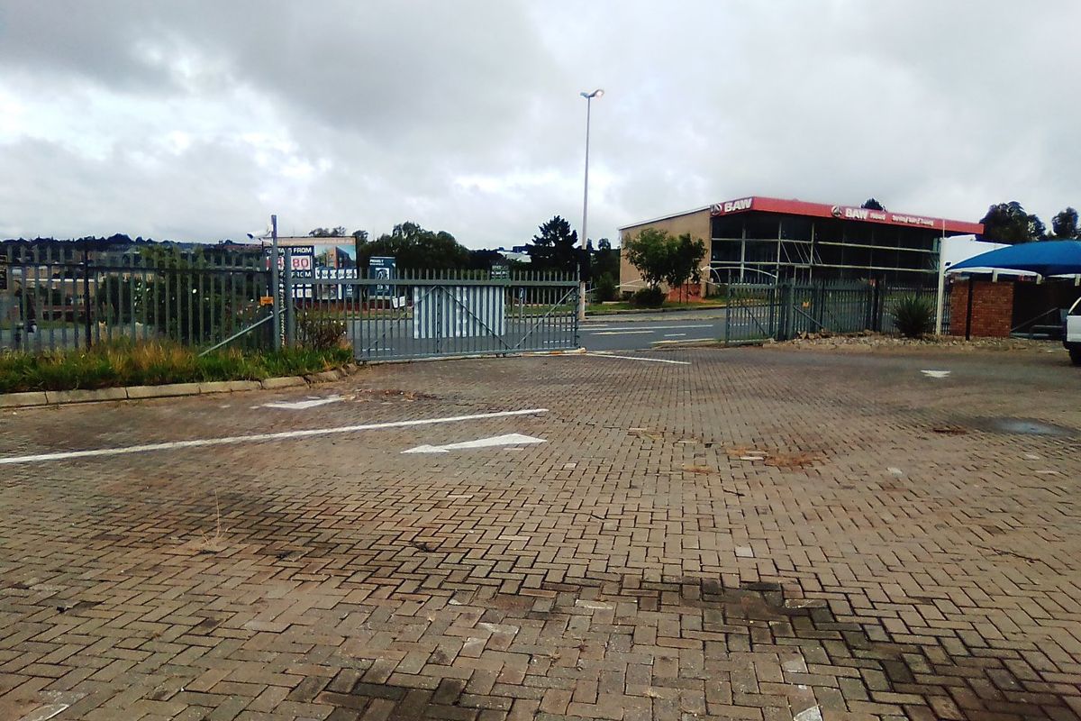 Commercial property entrance featuring a paved driveway, steel security gate, and perimeter fencing with street access.