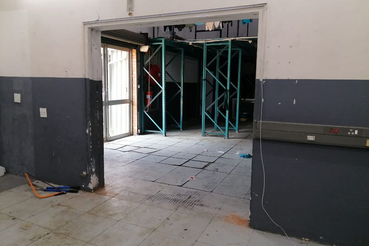 Industrial utility space featuring tiled flooring, fixed metal shelving units, and integrated electrical trunking, suitable for storage or workshop operations.