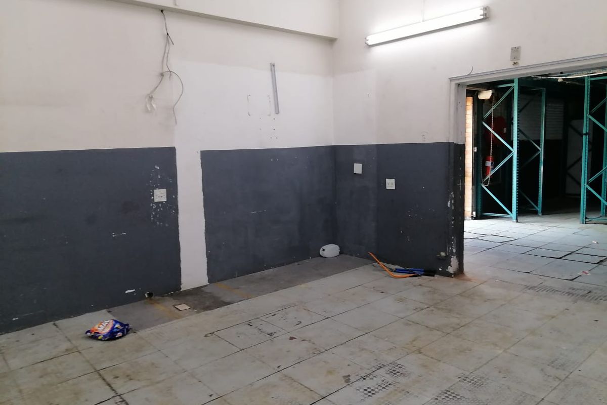 An empty industrial utility space featuring tiled flooring, fluorescent lighting, and dual-tone painted walls, suitable for storage or workshop use.