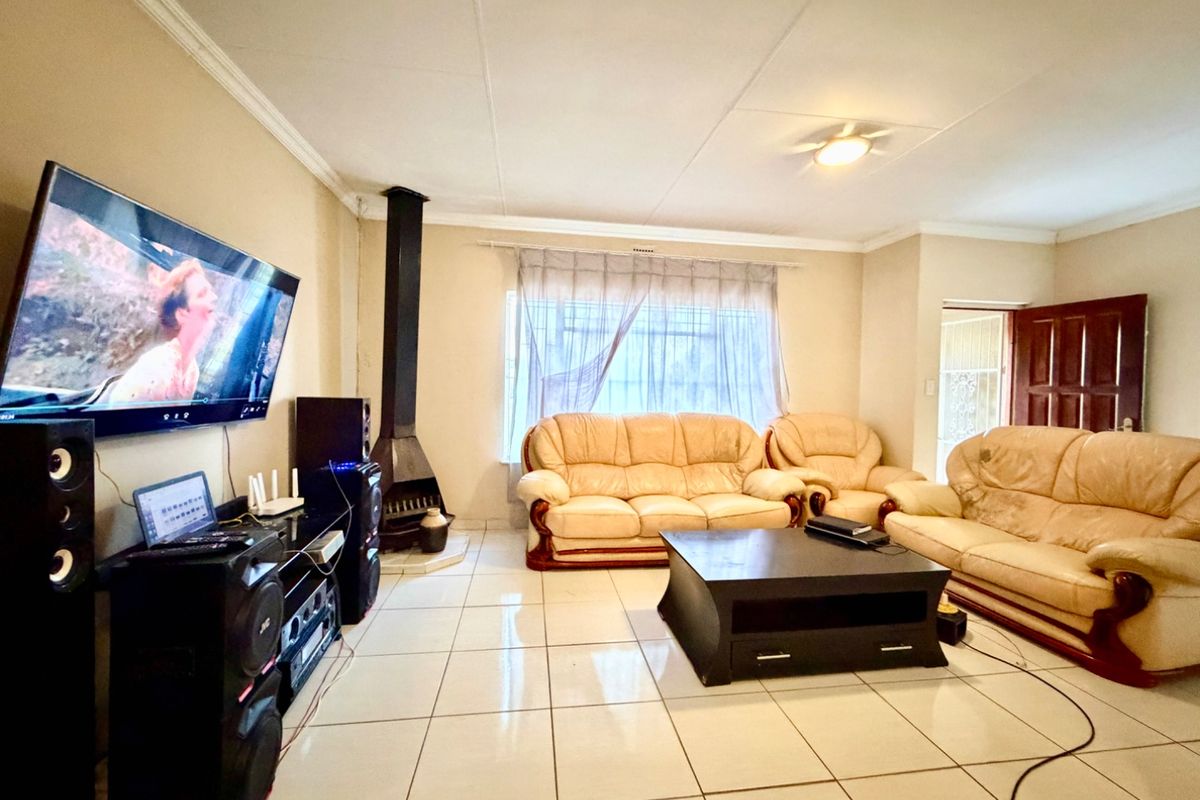 Spacious living room featuring tiled flooring, a freestanding fireplace, and neutral wall finishes, providing a comfortable and functional family area.