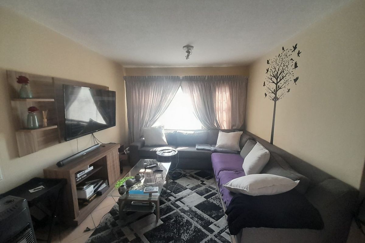 A cozy living room featuring a built-in media unit and large window with curtains, providing a comfortable space for relaxation.