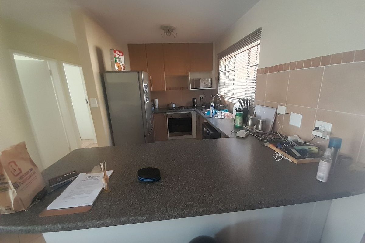 A functional kitchen featuring built-in cabinetry, laminate countertops, a built-in oven and hob, and a tiled backsplash with a breakfast bar area.