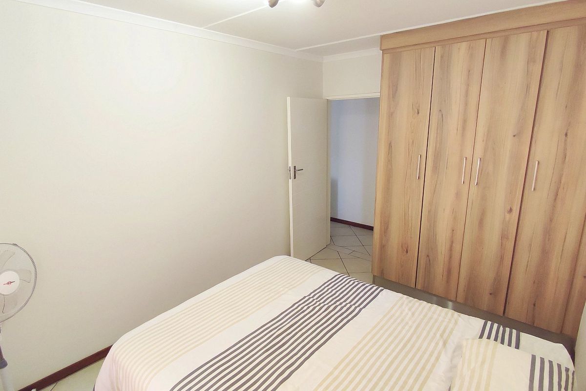 A bedroom featuring a large built-in wooden wardrobe and neutral wall finishes.