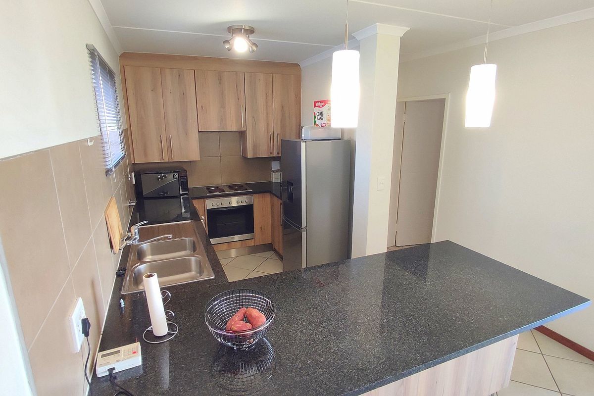 Functional kitchen featuring wood-finish cabinetry, granite countertops, a breakfast bar, and integrated appliances, offering a practical layout for daily cooking and dining.