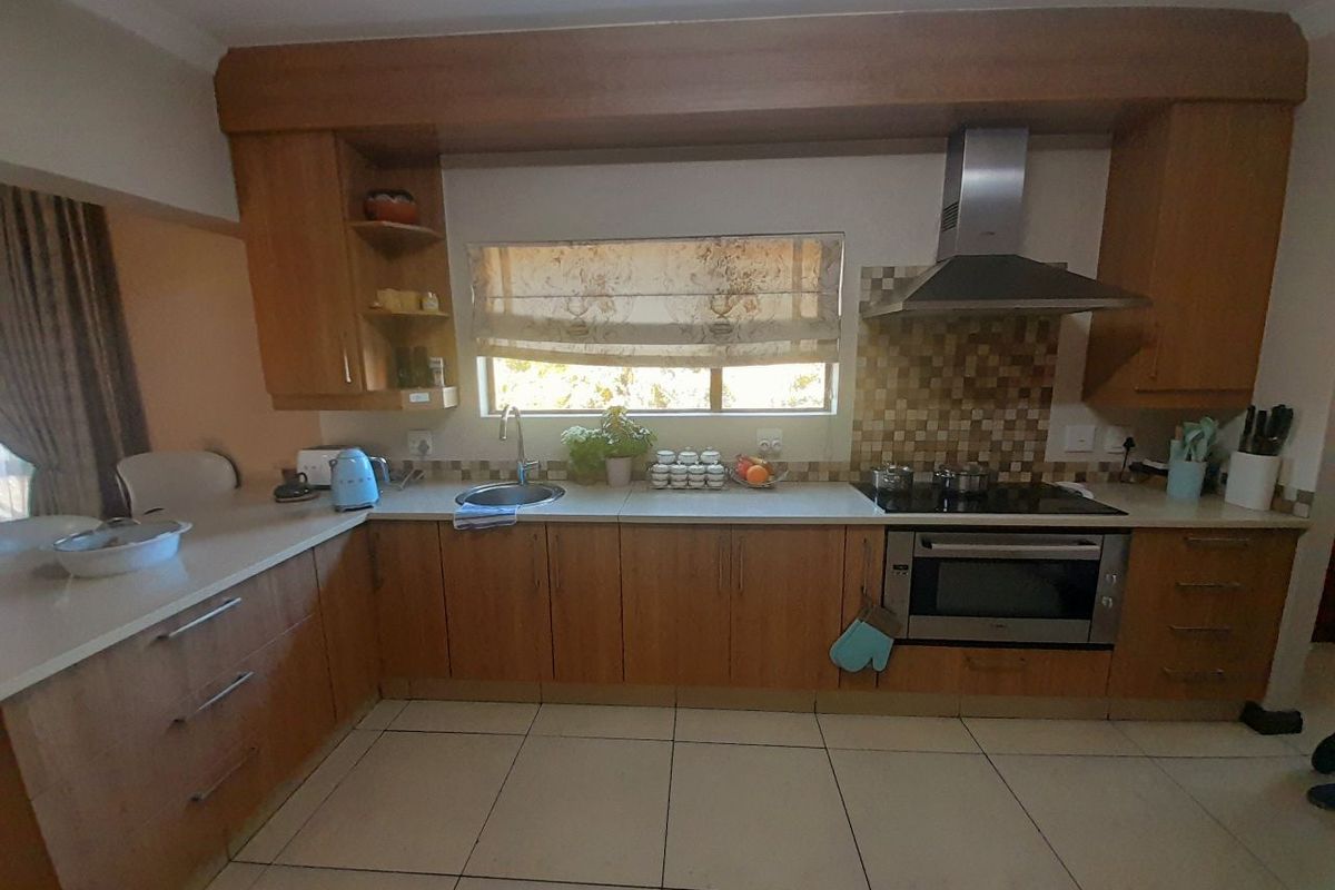 A functional kitchen featuring wooden cabinetry, a mosaic tile backsplash, integrated stainless steel appliances, and tiled flooring.