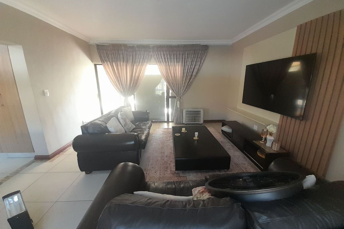 A comfortable living room featuring tiled flooring, a decorative feature wall with integrated television mount, and sliding glass doors leading to the exterior.
