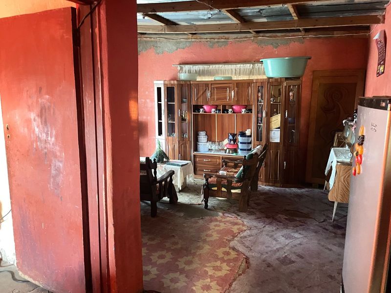A living area featuring exposed timber ceiling beams and tiled flooring, currently requiring significant renovation and finishing to improve the overall condition.