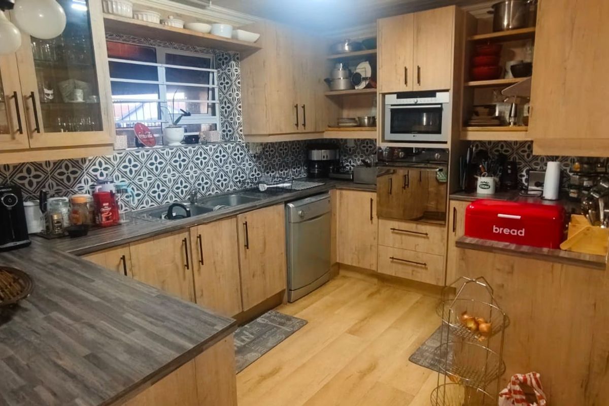 A functional kitchen featuring light wood-look cabinetry, patterned tile backsplash, integrated appliances, and durable laminate countertops with ample storage space.
