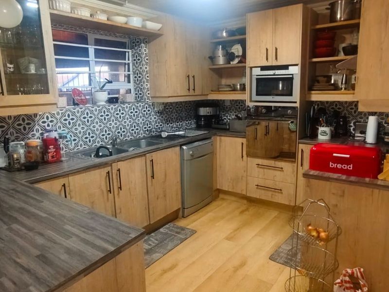 A functional kitchen featuring light wood-look cabinetry, patterned tile backsplash, integrated appliances, and durable laminate countertops with ample storage space.