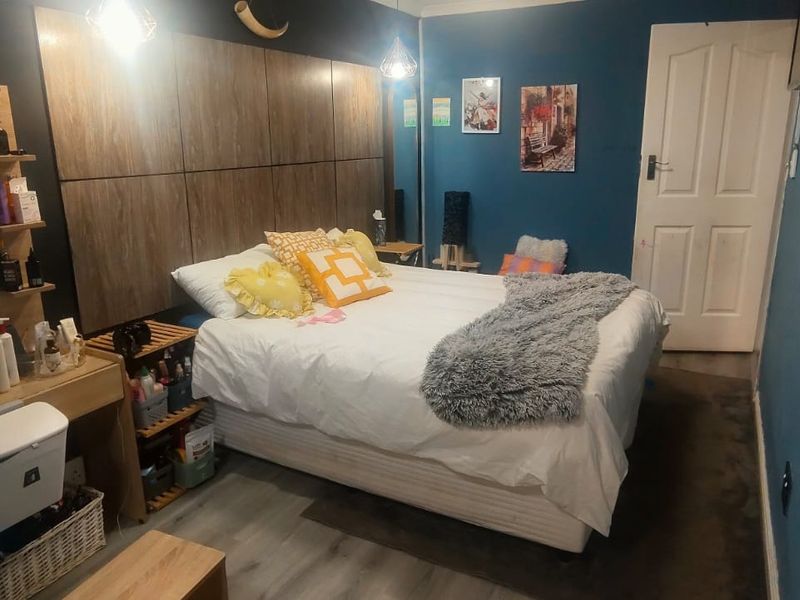 A bedroom featuring a large built-in headboard, laminate flooring, and blue accent walls.