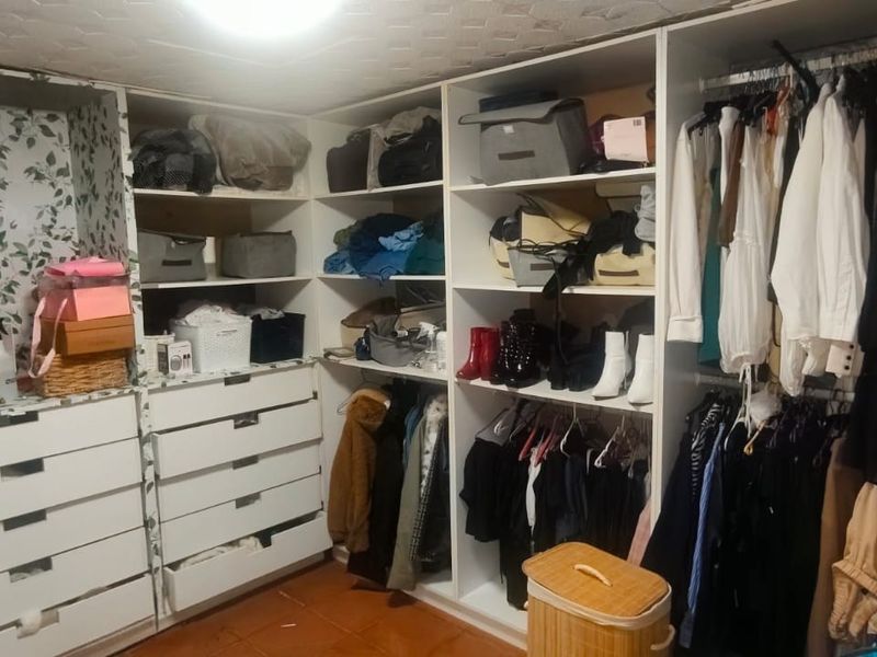 A walk-in closet or bedroom storage area featuring extensive built-in cabinetry, shelving, and hanging space for organized clothing storage.
