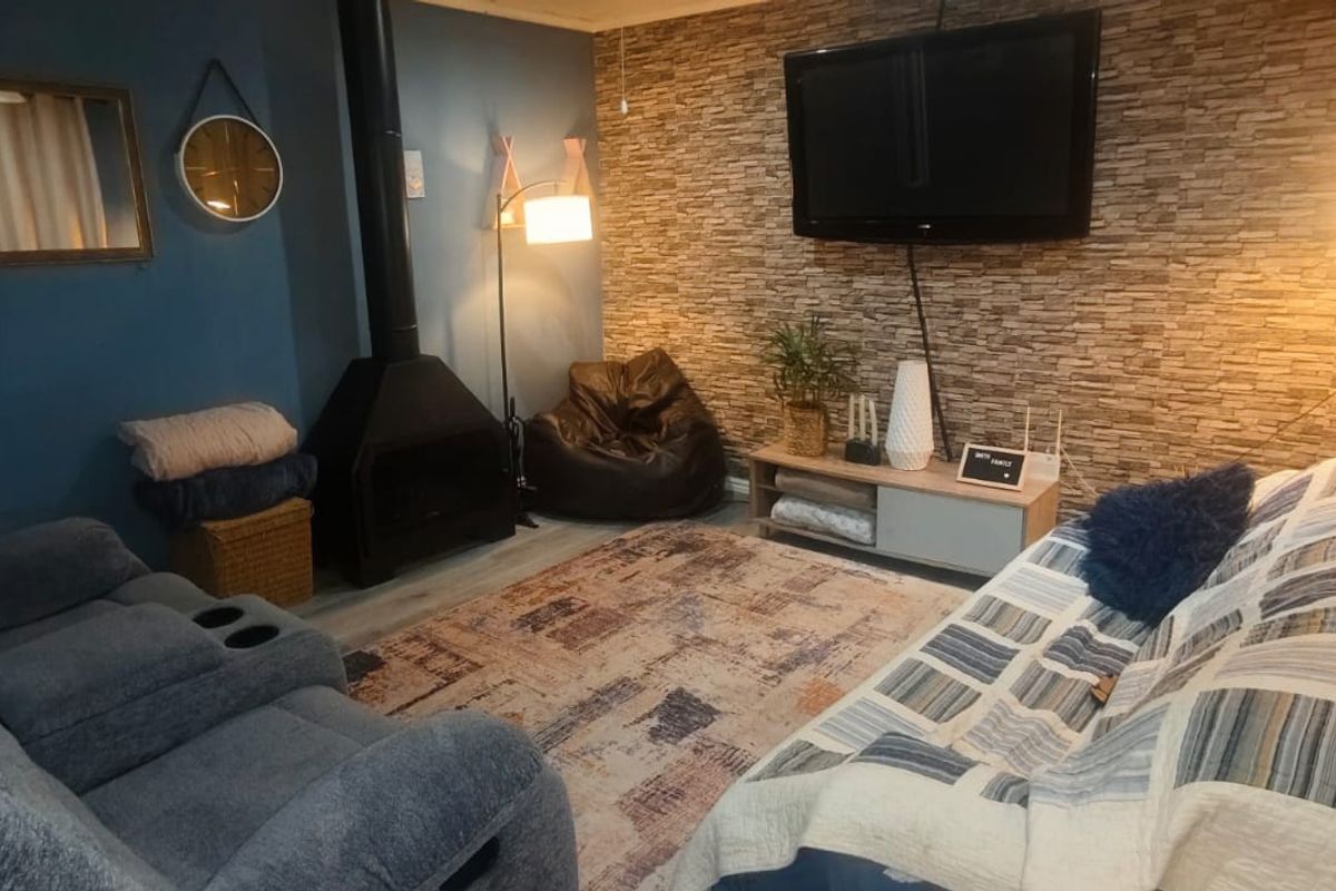 Cozy living room featuring a stone veneer accent wall, a modern freestanding fireplace, and durable laminate flooring.