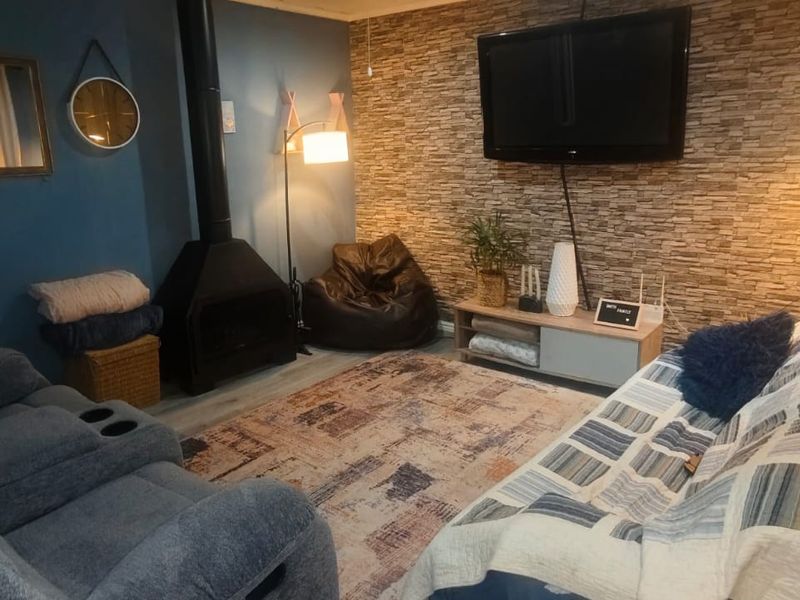 Cozy living room featuring a stone veneer accent wall, a modern freestanding fireplace, and durable laminate flooring.