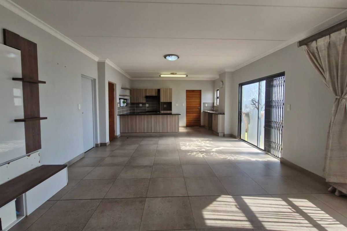 Spacious open-plan living and kitchen area featuring large floor tiles, modern cabinetry, and sliding doors leading to the exterior.