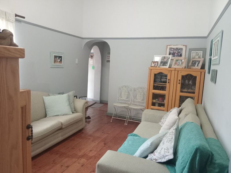 A cozy living room featuring original hardwood flooring, a classic archway entrance, and traditional picture rail detailing.