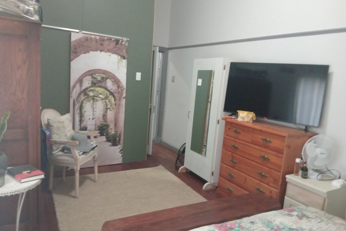 A bedroom featuring hardwood flooring and a classic picture rail, offering a functional space with neutral wall tones.