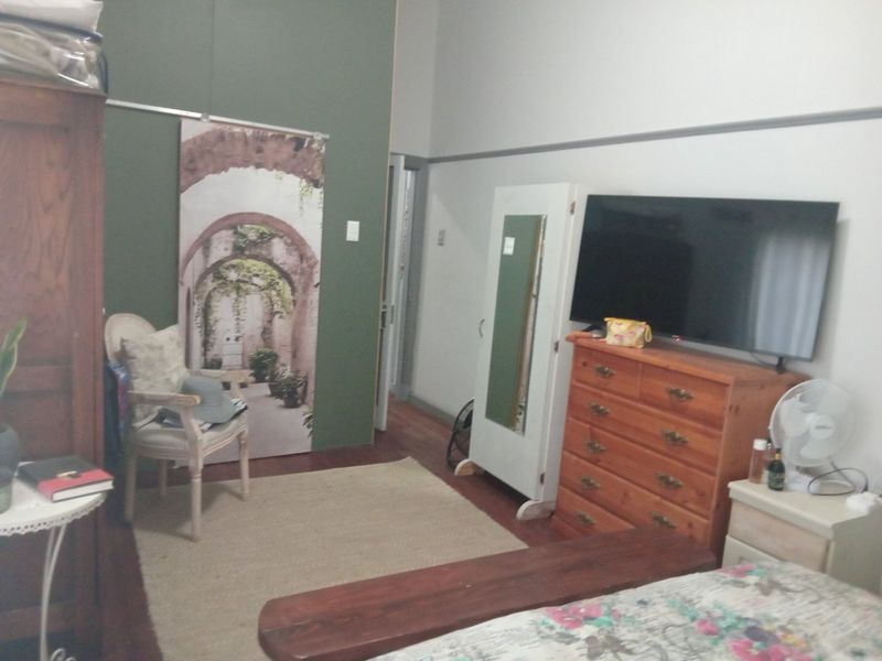 A bedroom featuring hardwood flooring and a classic picture rail, offering a functional space with neutral wall tones.