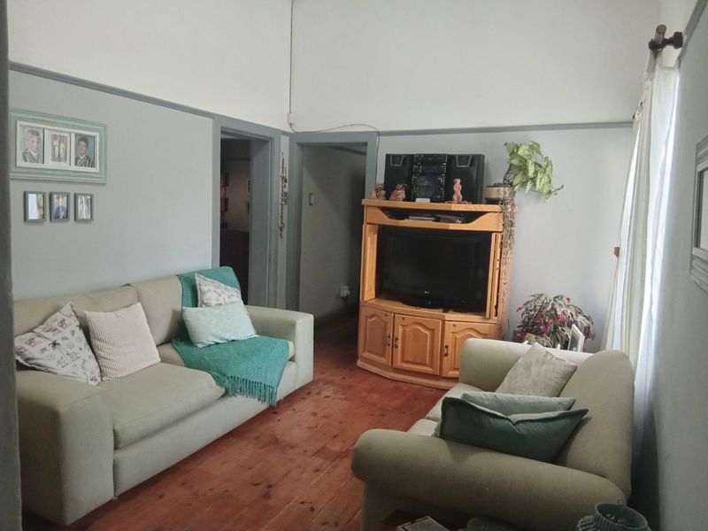 A living room featuring high ceilings, classic picture rails, and original timber flooring, offering a character-filled space with potential for modern updates.