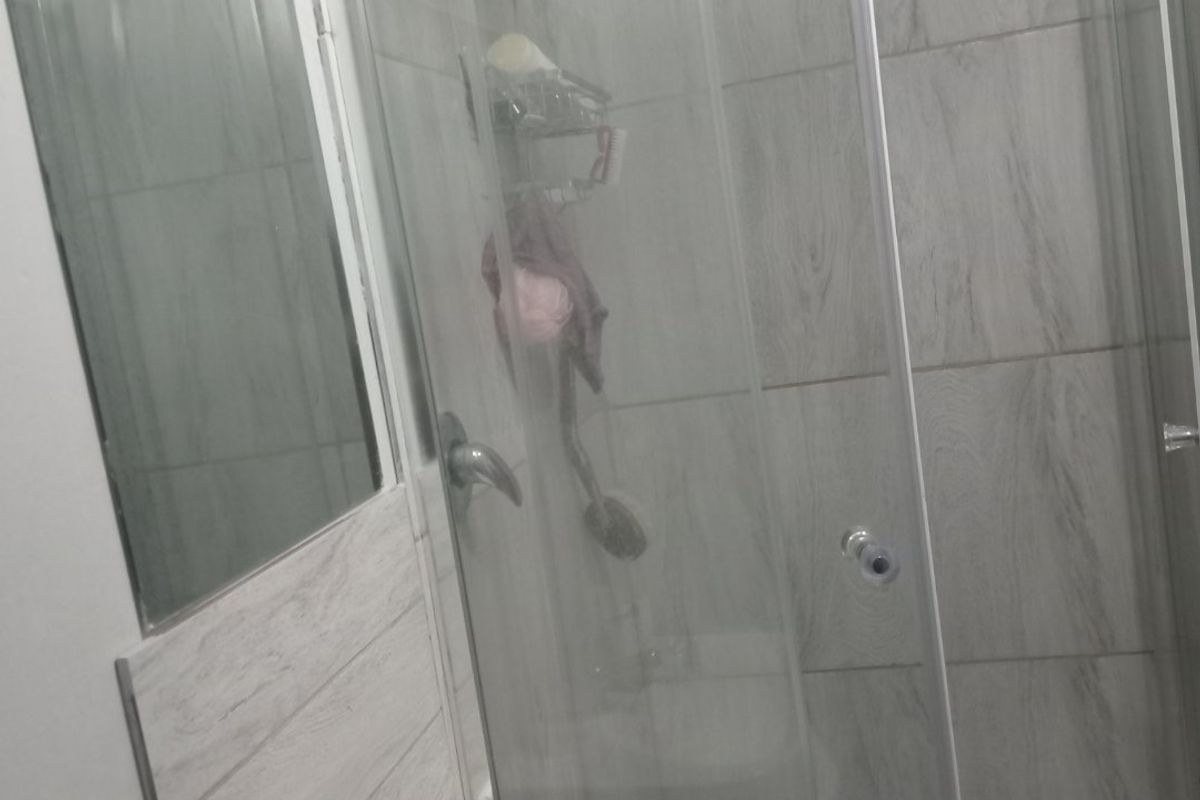 A compact bathroom featuring a modern glass shower enclosure with a rain shower head and a wall-mounted basin with chrome fixtures.