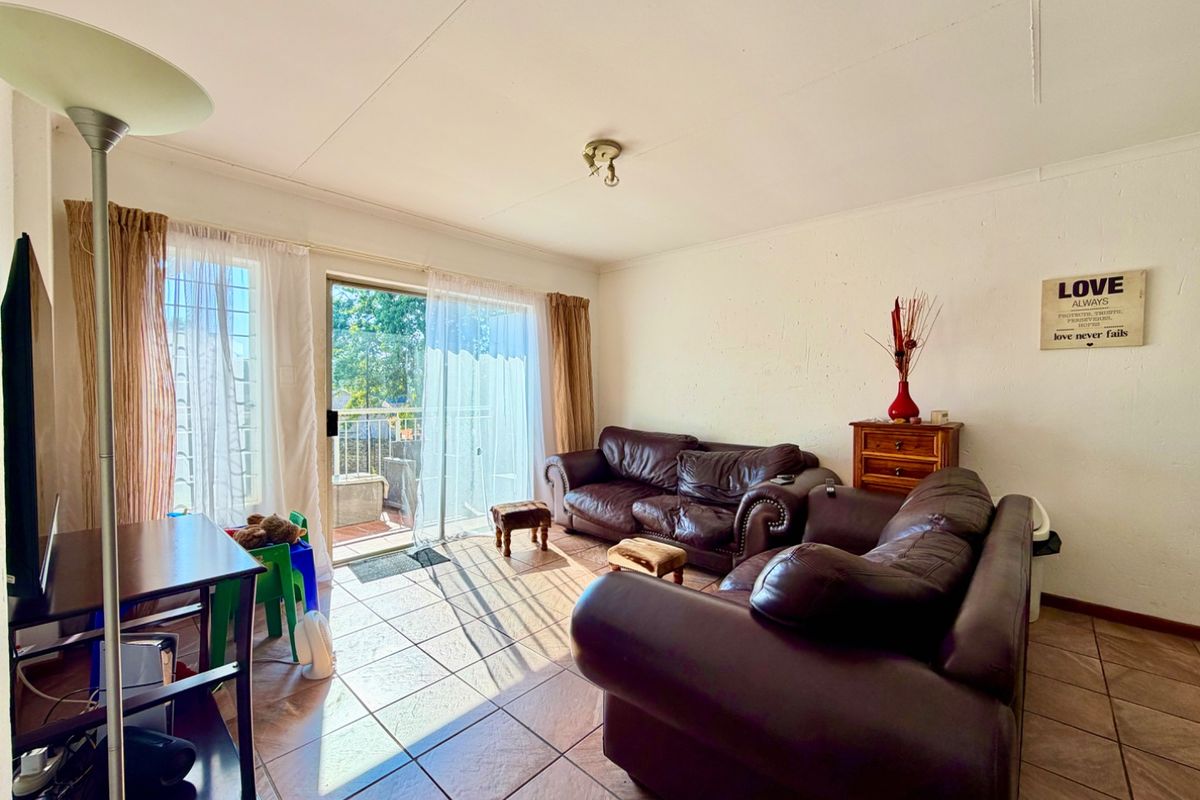 A living room featuring tiled flooring and a sliding glass door that provides access to an outdoor balcony area.
