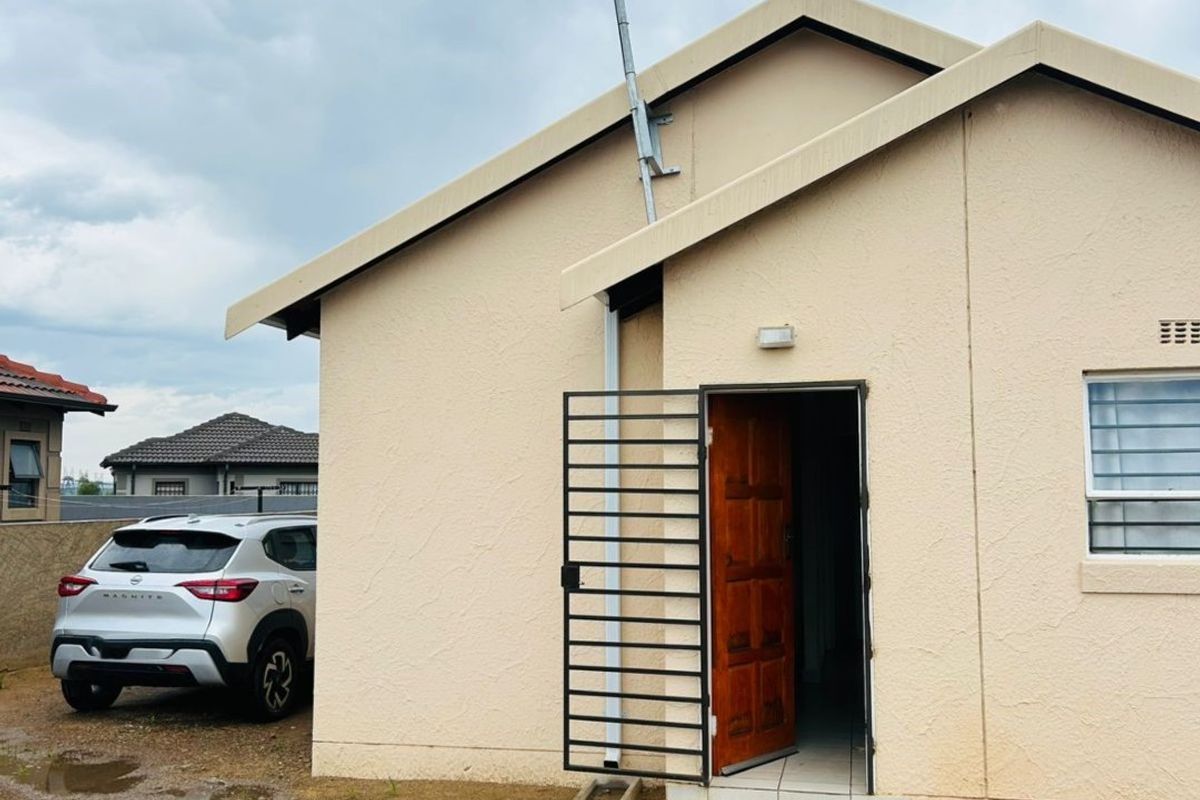 Exterior view of the house entrance featuring a security gate, tiled threshold, and roof-mounted communication antenna.