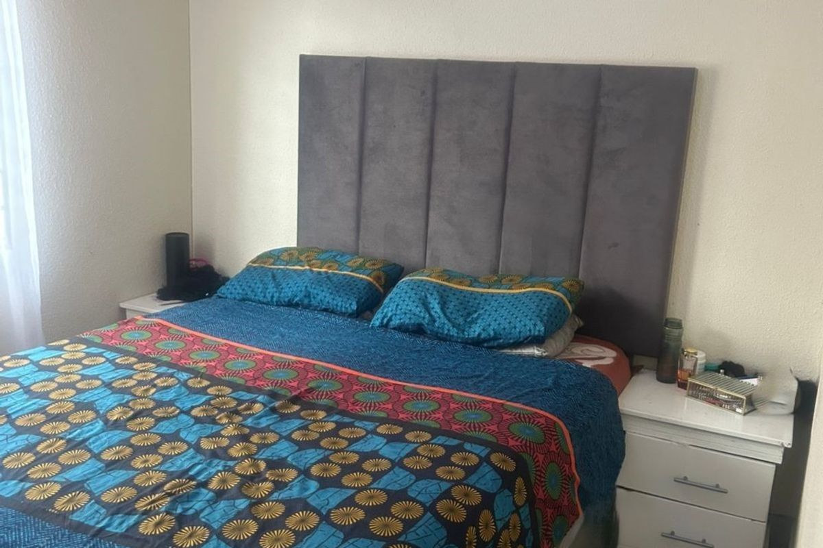 A functional bedroom featuring tiled flooring and a neutral wall finish, providing a simple and practical living space.