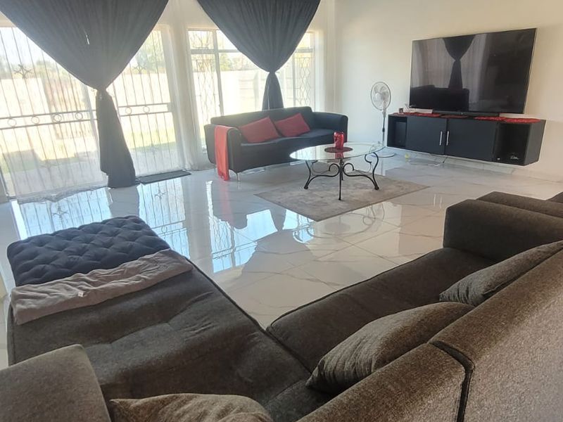 Spacious living room featuring large format floor tiles, a dark timber-clad ceiling, and sliding glass doors providing access to the exterior.