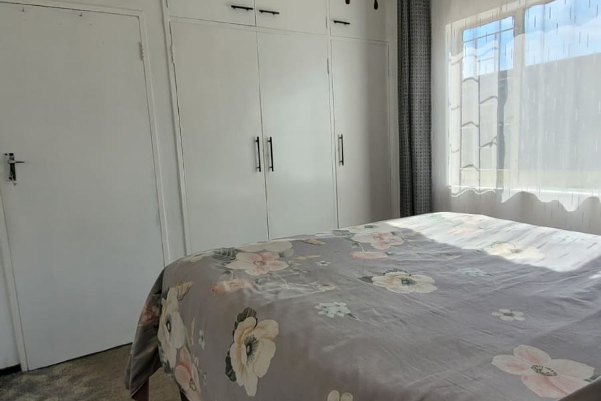 A bedroom featuring built-in white cabinetry, a ceiling fan, and carpeted flooring, offering a functional and neutral living space.