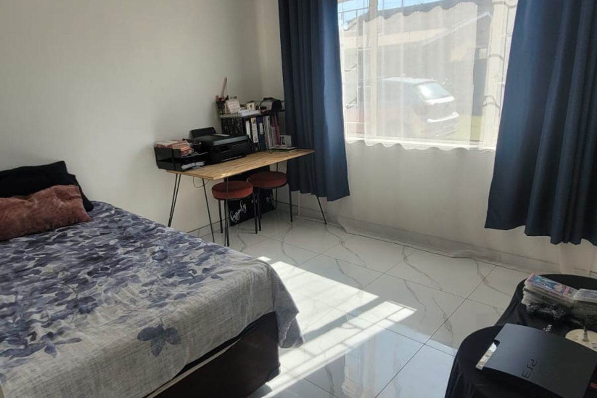 A bright bedroom featuring large-format marble-look floor tiles, a white tongue-and-groove ceiling, and a ceiling fan.