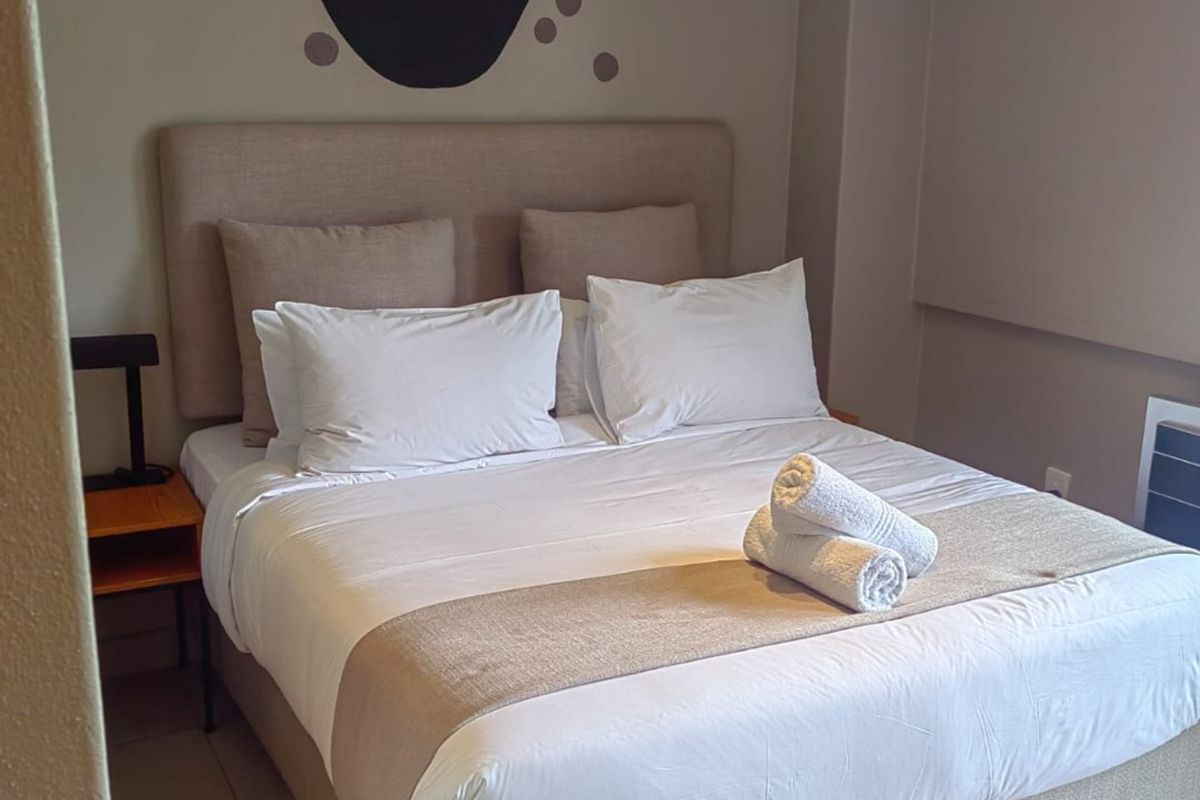 A bedroom featuring tiled flooring and neutral wall tones, providing a functional and comfortable sleeping space.
