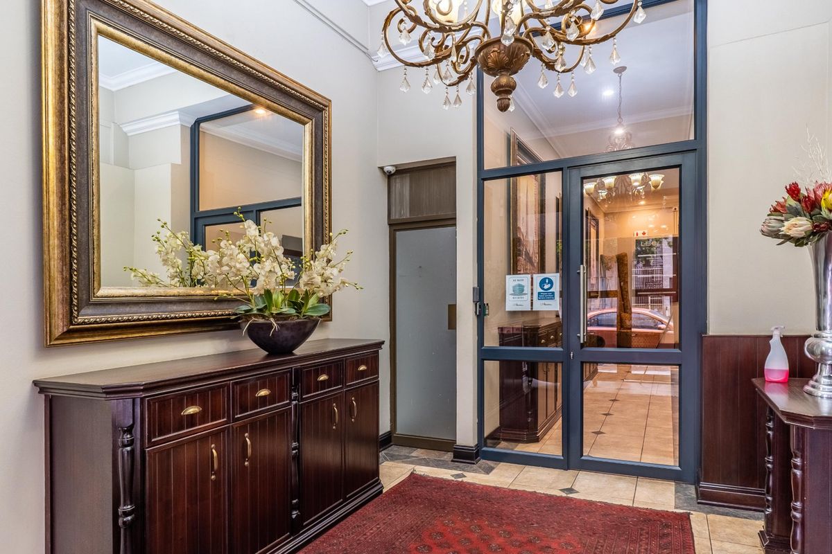 A professional commercial entrance foyer featuring tiled flooring, a glass-paneled door, decorative crown molding, and a classic chandelier.