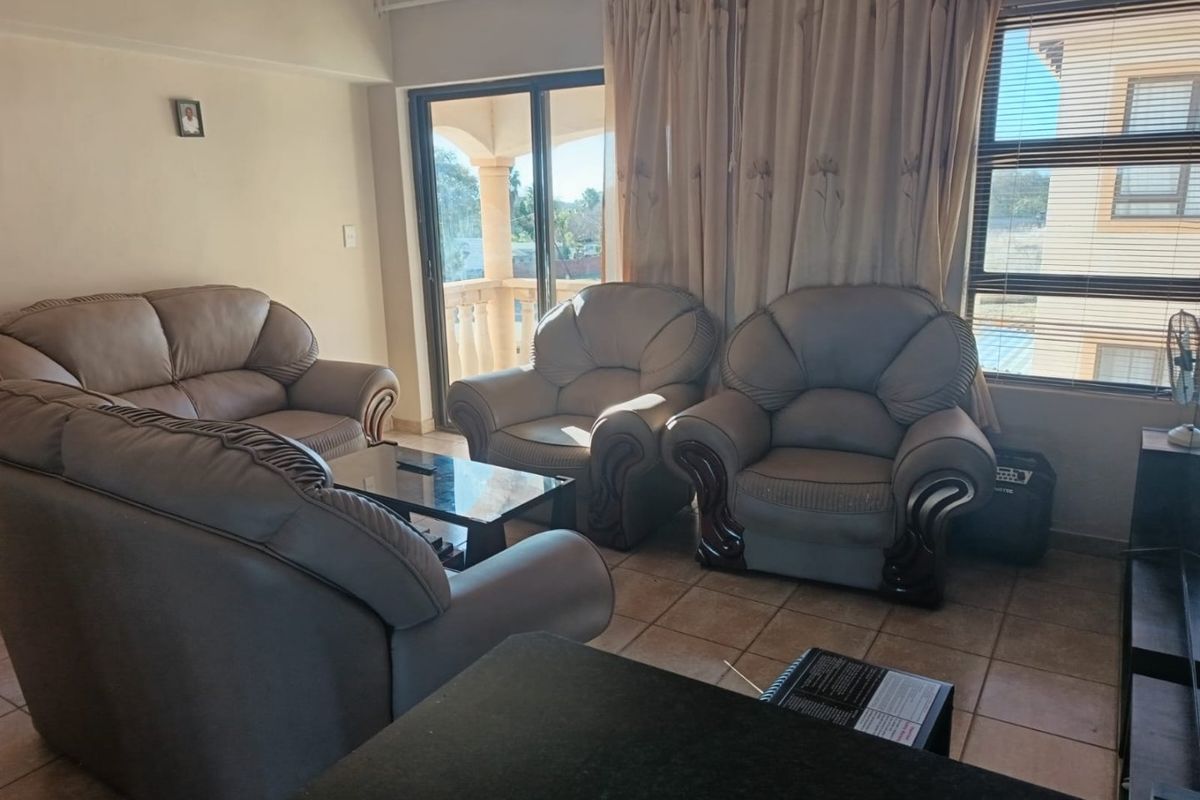 A living room area featuring tiled flooring, large sliding glass doors leading to a balcony, and window blinds.
