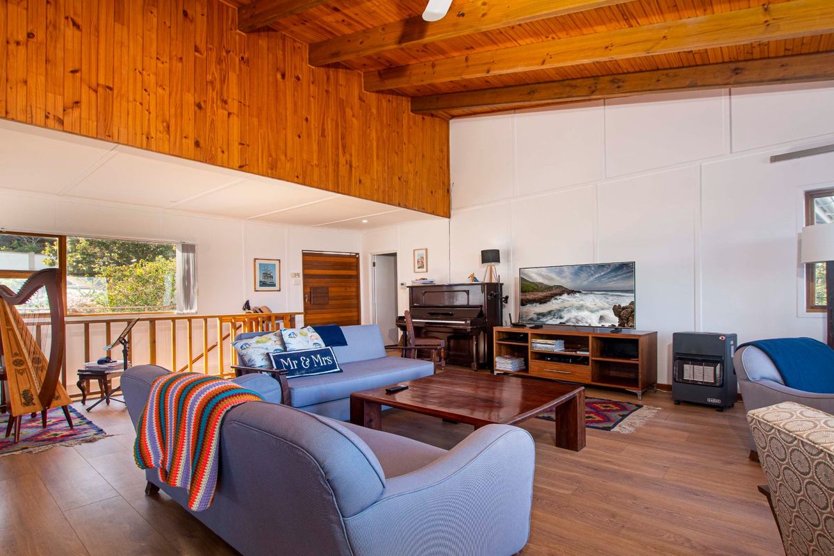 Spacious living room featuring high vaulted timber ceilings, exposed wooden beams, and durable laminate flooring, creating a warm and inviting atmosphere.
