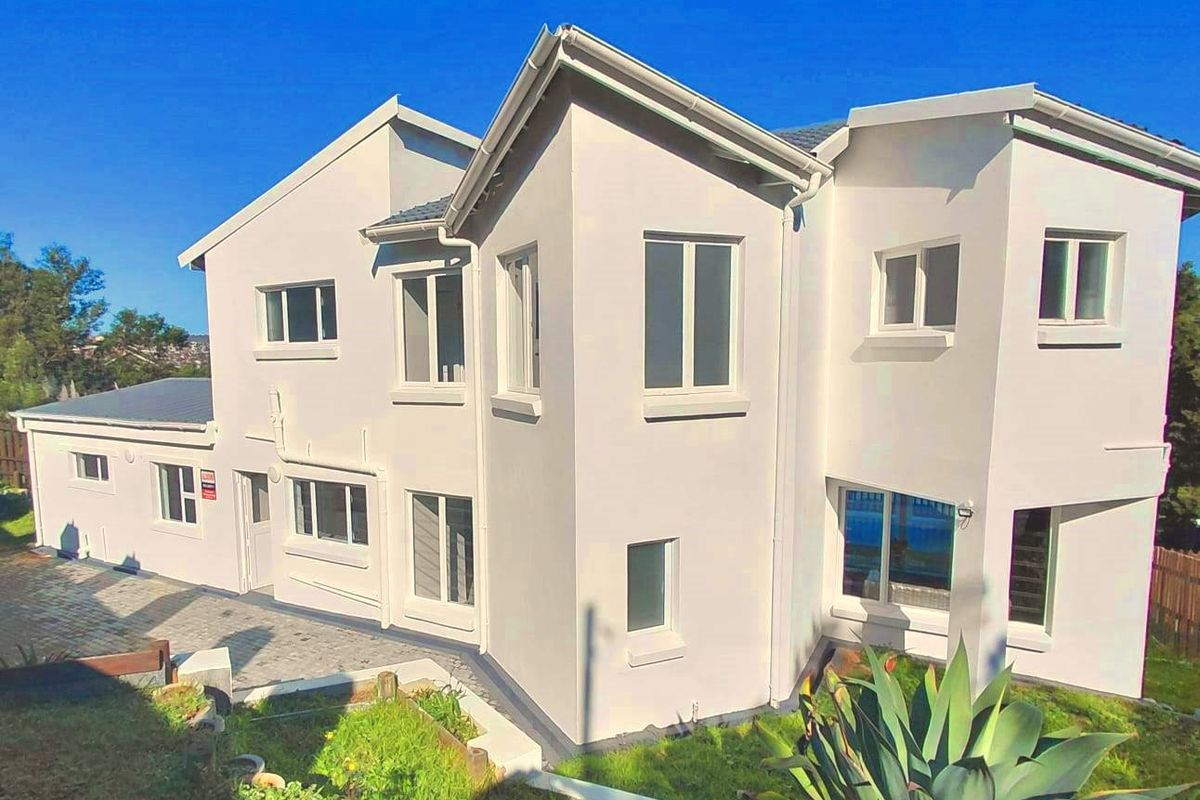 A well-maintained two-story residential house featuring a modern light-colored facade, tiled roof, and paved exterior pathways.