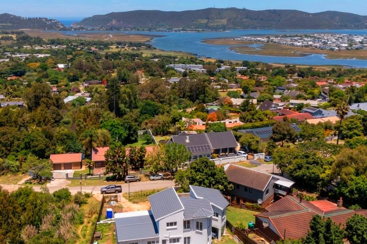 Aerial view of the property showcasing its location within a lush, green residential neighborhood with scenic views of the nearby estuary and landscape.