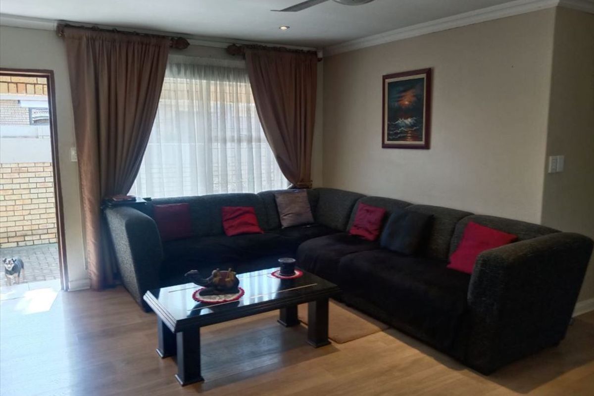A comfortable living room featuring laminate flooring, a ceiling fan, and direct access to an outdoor patio area.