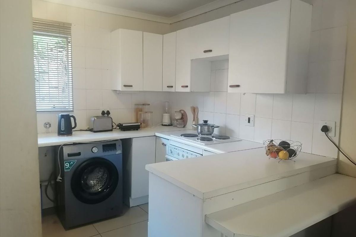Functional kitchen featuring white cabinetry, integrated stove and hob, tiled flooring, and a dedicated space for a washing machine.
