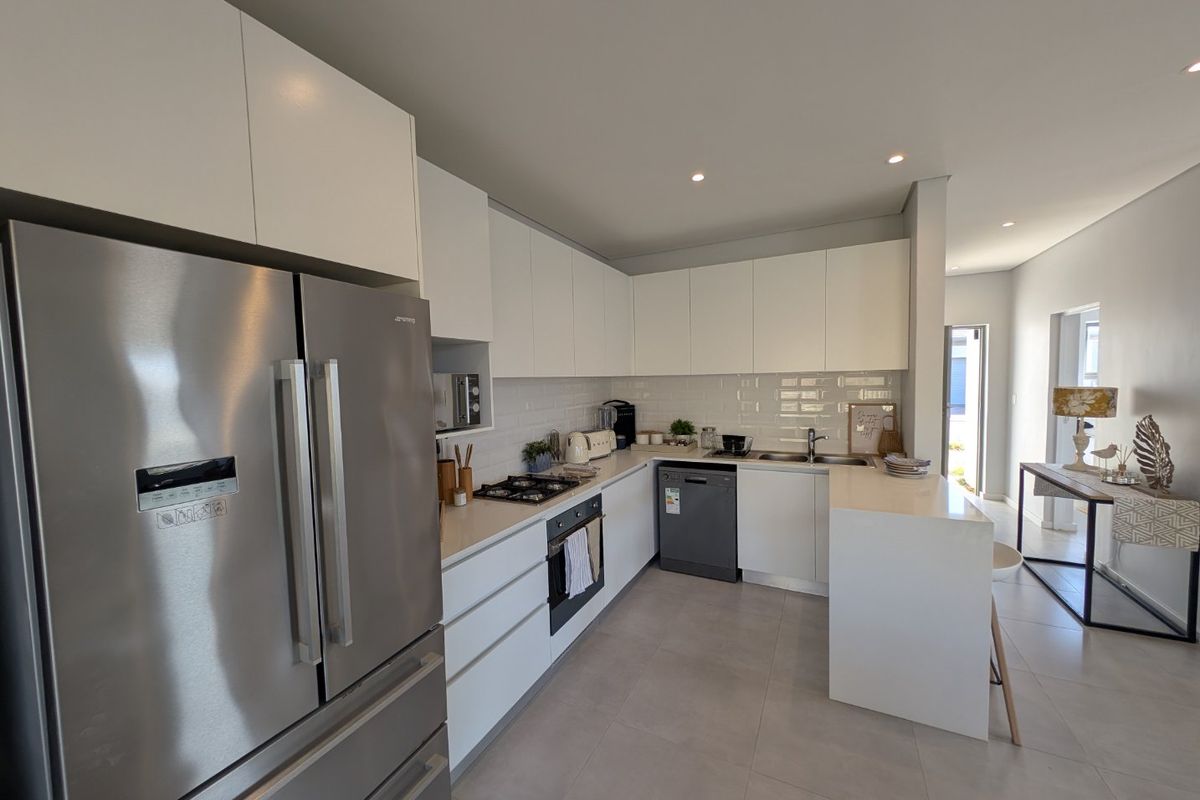 Modern kitchen featuring white cabinetry, stone countertops, subway tile backsplash, integrated oven, gas hob, and stainless steel appliances.