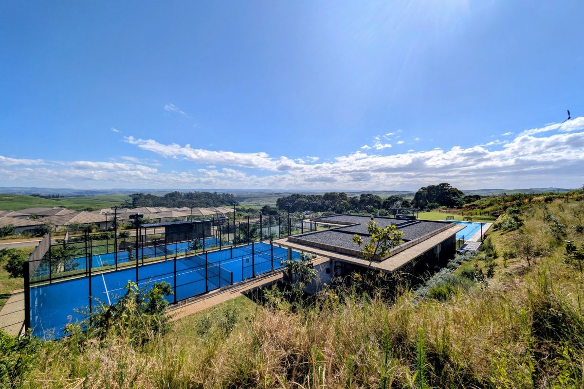 Aerial view of the apartment complex amenities, featuring well-maintained padel courts and a swimming pool set within a landscaped estate.