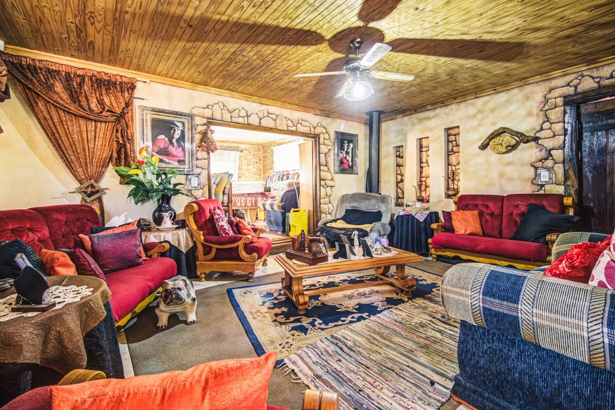 A living room featuring a timber-clad ceiling, ceiling fan, and decorative stone-effect wall detailing, leading into an adjacent room.