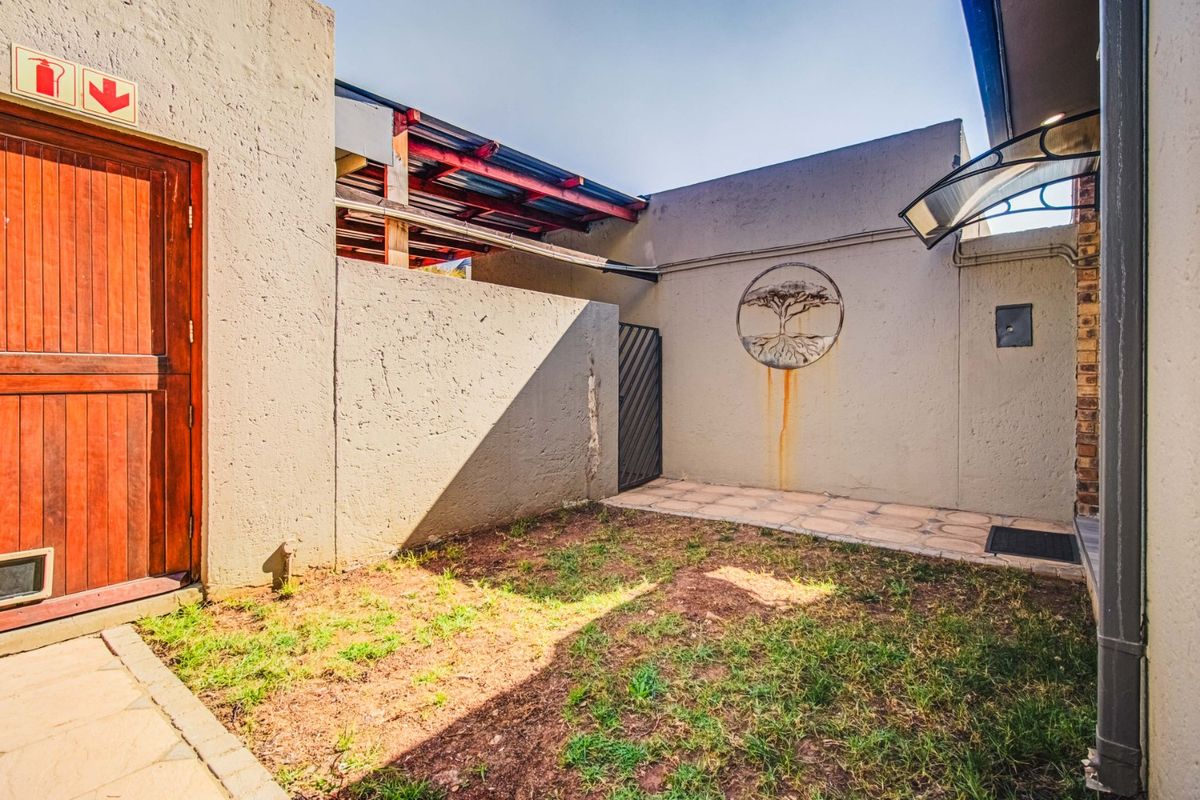 A private rear courtyard featuring a paved patio area, boundary walls, and a small lawn space with potential for landscaping improvements.